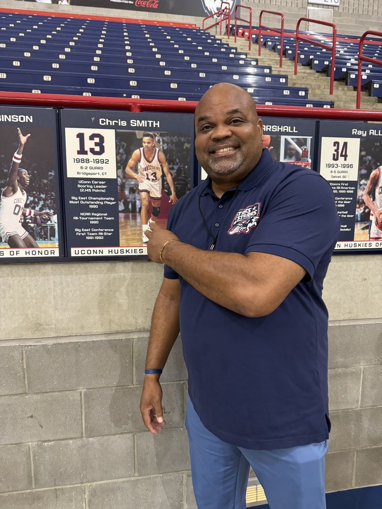 Chris Smith at the UConn Huskies of Honor wall, next to his own retired-jersey display